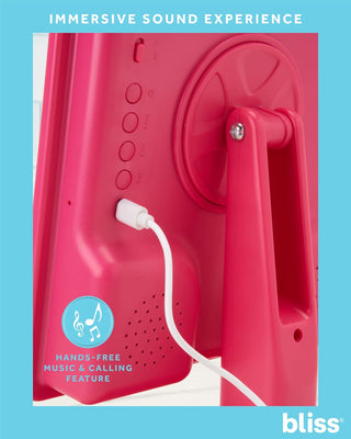 The image shows the back of a pink device, identified as the LED Vanity Mirror with Built-In Speaker & Hands-Free Calling, with a white cord plugged into it. Text on the image reads "IMMERSIVE SOUND EXPERIENCE" and "HANDS-FREE MUSIC & CALLING FEATURE." The bliss® logo is displayed in the bottom right corner.