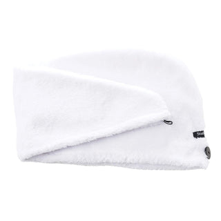 A white, soft, and fluffy winter headwear resembling a beanie with a fold-over design is shown. It has a black label with text near the fold and a button detail on one end. Made from cozy microfiber material akin to Studio Dry's 20X QuickDry Turban Hair Towel (2-Pack), it's perfect for cold weather warmth.