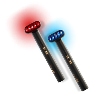 Two GLO24K 6-in-1 Facial Therapy Wands featuring cylindrical black handles: one with a red LED light at the top and the other with a blue LED light. Both devices boast gold detailing and buttons on the handles, suggesting they utilize micro-current technologies for anti-aging benefits and skin care treatments.