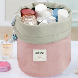 A pink and beige Waterproof Makeup Organizer Travel Bag from the Amore Paris brand, filled with various skincare and cosmetic bottles, jars, and containers. Next to the chic waterproof bag is a cream-colored bottle of perfume and an open pink jar.