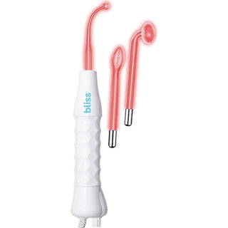 A white handheld skincare device by "bliss" that includes a textured grip and a long cord. The High Frequency Electrotherapy & Facial Wand comes with a pink applicator attached, as well as two extra interchangeable pink metal-tipped applicators on the right, making it perfect for high-frequency electrotherapy and acne treatment.