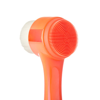 Close-up of the "Cleanse It" 2in1 Exfoliator Brush (2-Pack) by Almost Famous, showcasing its dual-sided design with a vibrant orange handle. One side boasts soft, white bristles, while the opposite side features red silicone bristles arranged in concentric circles—ideal for addressing clogged pores. The background is plain white.