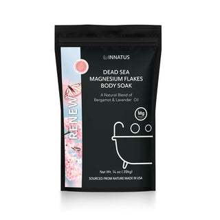 A black, resealable bag labeled "Pure Dead Sea Renewal Soak with Magnesium Flakes" by INNATUS, features Pure Dead Sea Magnesium Flakes combined with a natural blend of bergamot and lavender oil. The minimalist design showcases an icon of a bathtub and pink decorative elements on the side. Net weight: 14 oz (397 g).